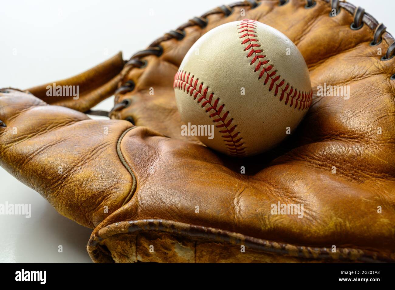 A white leather baseball in a brown vintage, antique glove Stock Photo