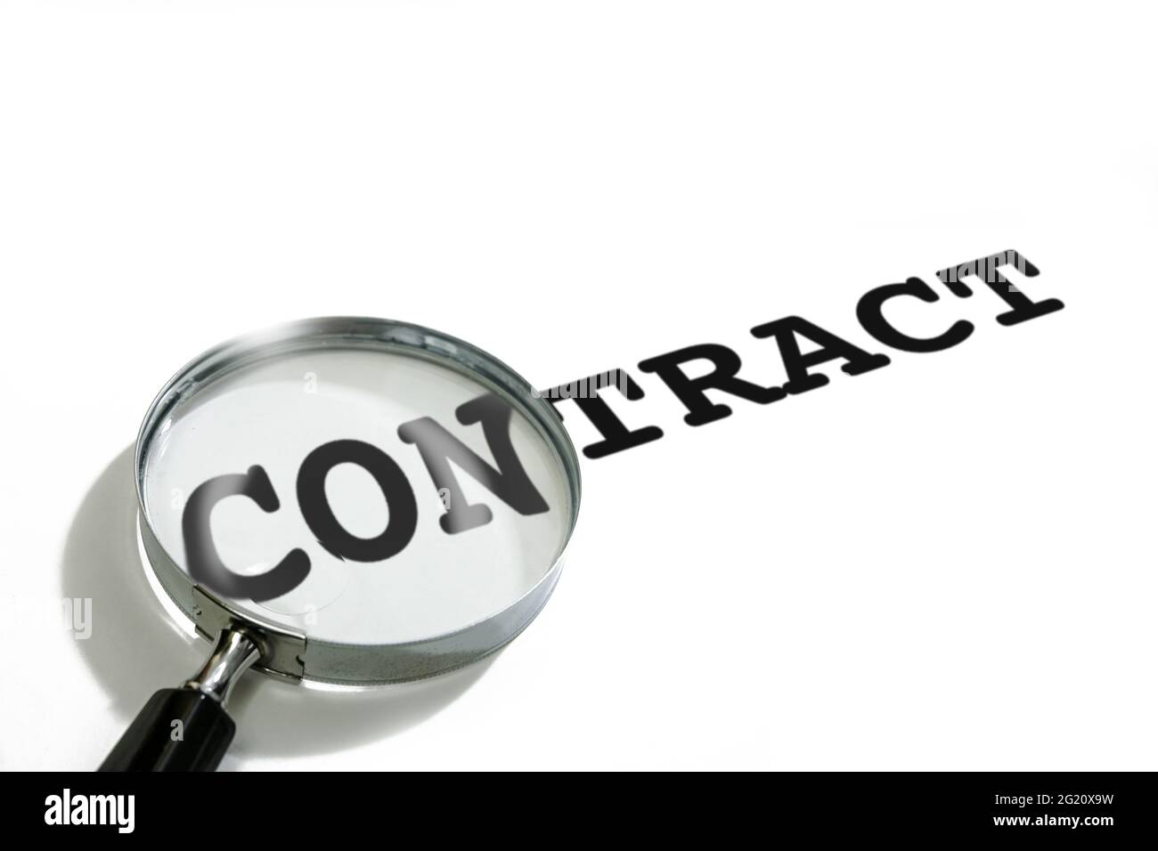 The magnifying glass is placed on the CON part of the word CONTRACT. Stock Photo