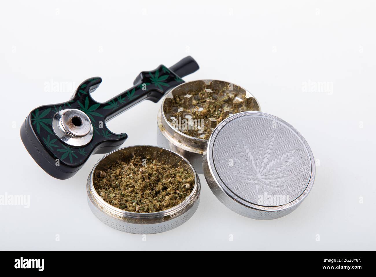 Cannabis pipe with hemp leaves drawings on it and a grinder with cannabis in it  Stock Photo