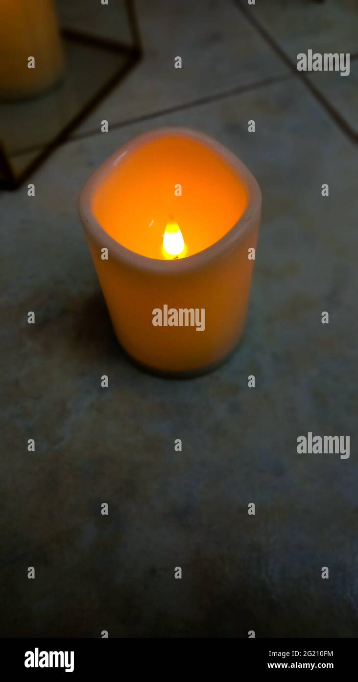 plastic electric candle on floor glowing with yellow flame,home related decoration element, Stock Photo