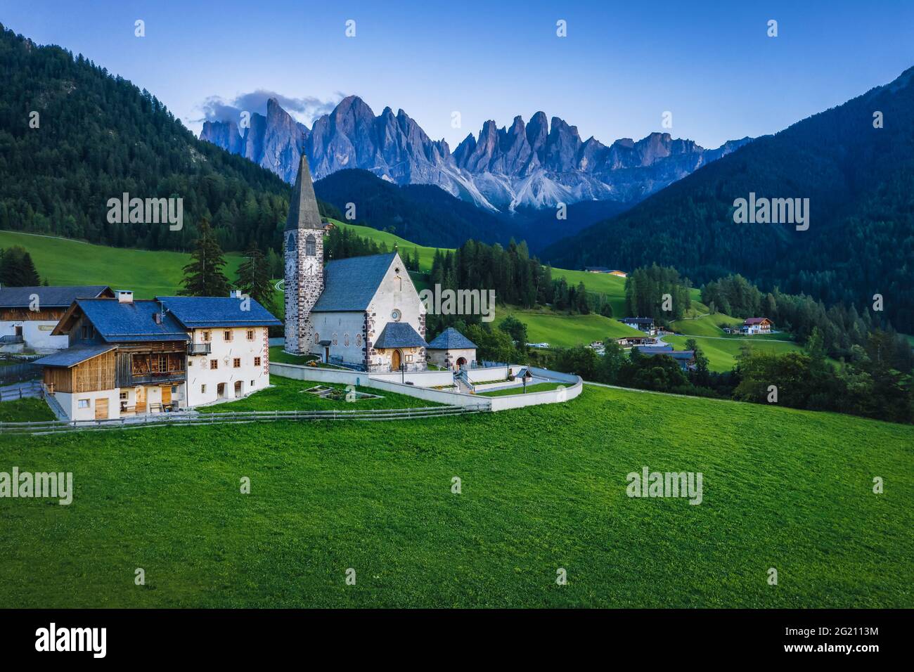 St Magdalena church in Val di Funes valley in evening dusk light, Dolomites, Italy. Furchetta and Sass Rigais mountain peaks in background Stock Photo