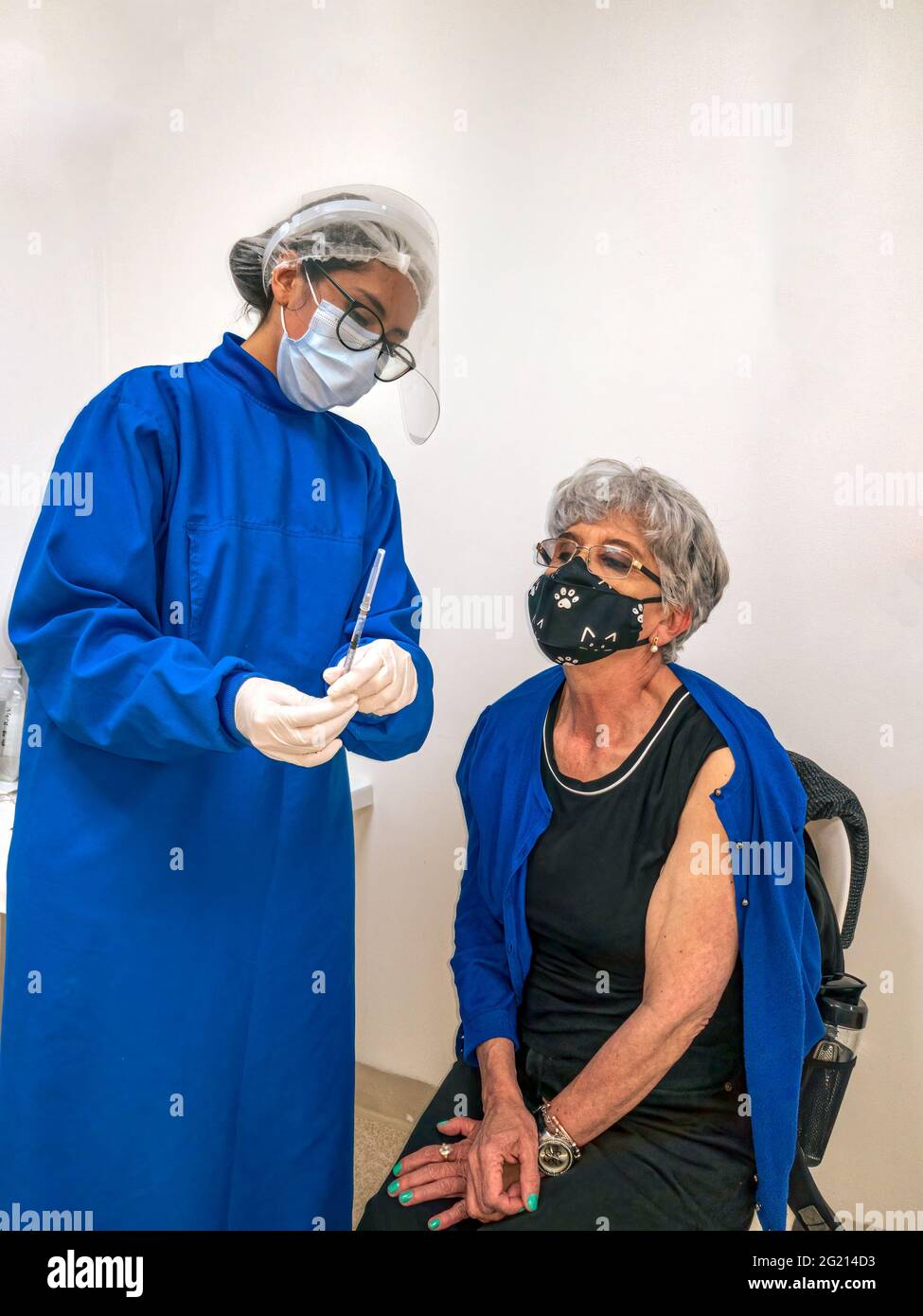 Bogota, Colombia - Image shows a senior Latin American lady of Colombian ethnicity being vaccinated against Covid-19 in the Andean capital city at a vaccination centre. The nurse is seen explaining the antivirus and the dosage to the lady. Image shot on mobile devise. Stock Photo