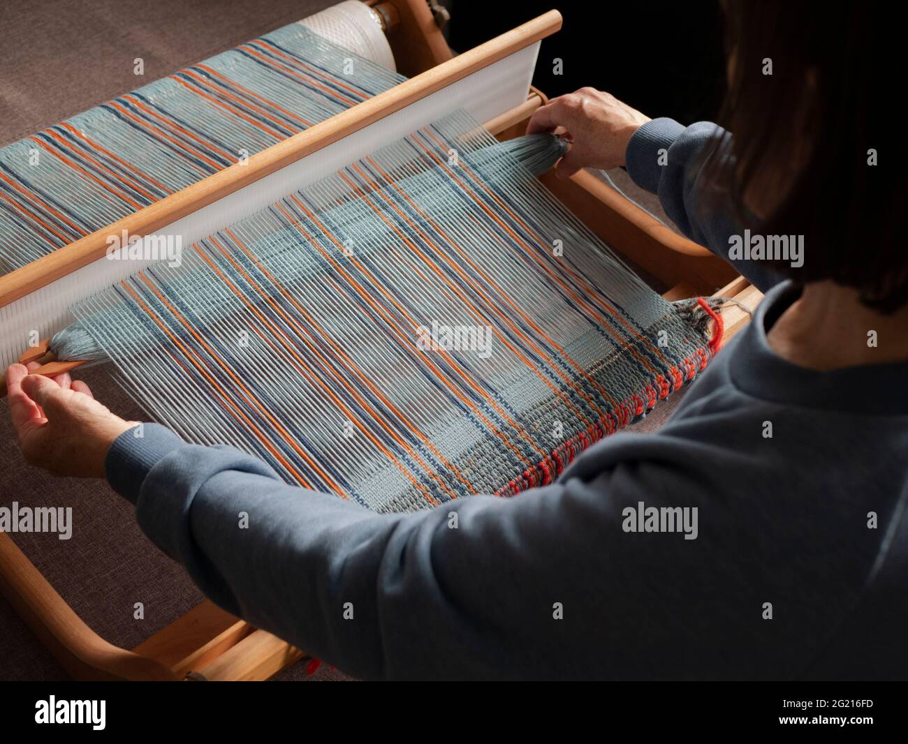 Handloom weaver is working. Making a striped fabric using weaving loom
