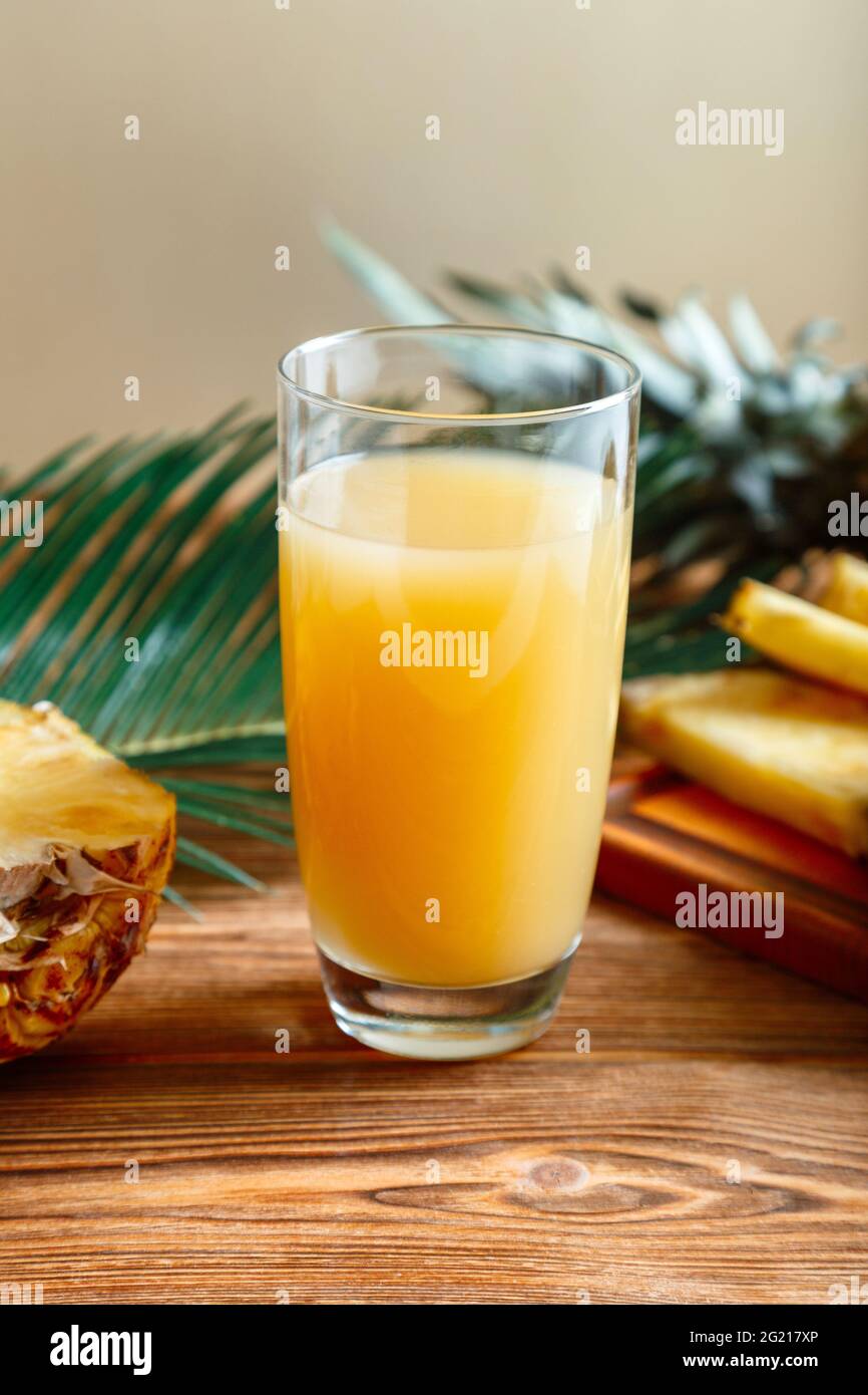 Pineapple juice. Glass of fresh natural pineapple juice on brown wooden table with ingredients. Fruit citrus orange fresh juice drink. Raw pineapple Stock Photo