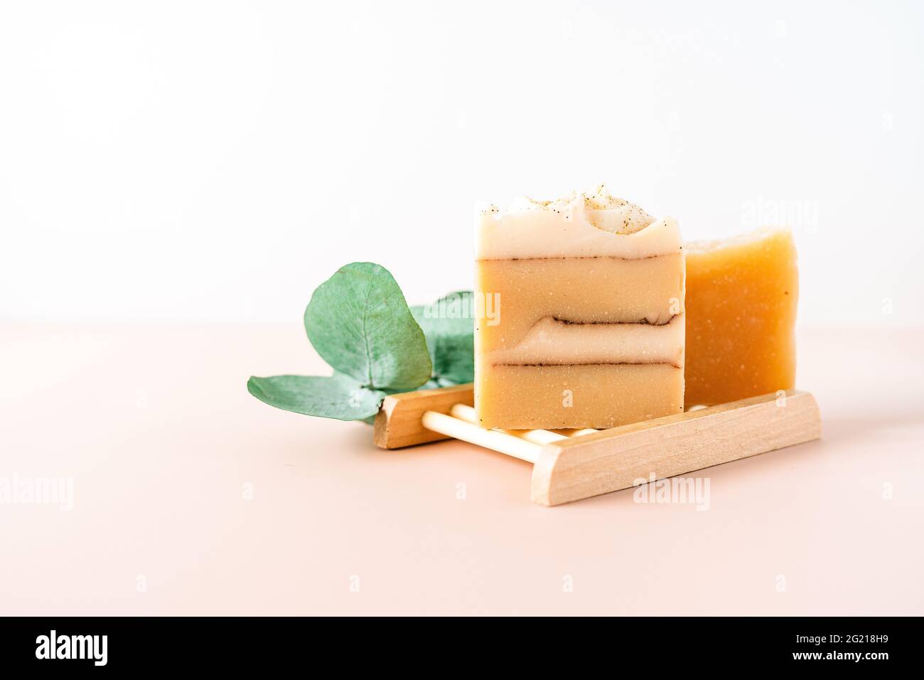 Homemade Soap with eucalyptus plant in wooden soap dish on white marble background. Zero waste, natural organic bathroom cosmetics. Plastic free life Stock Photo