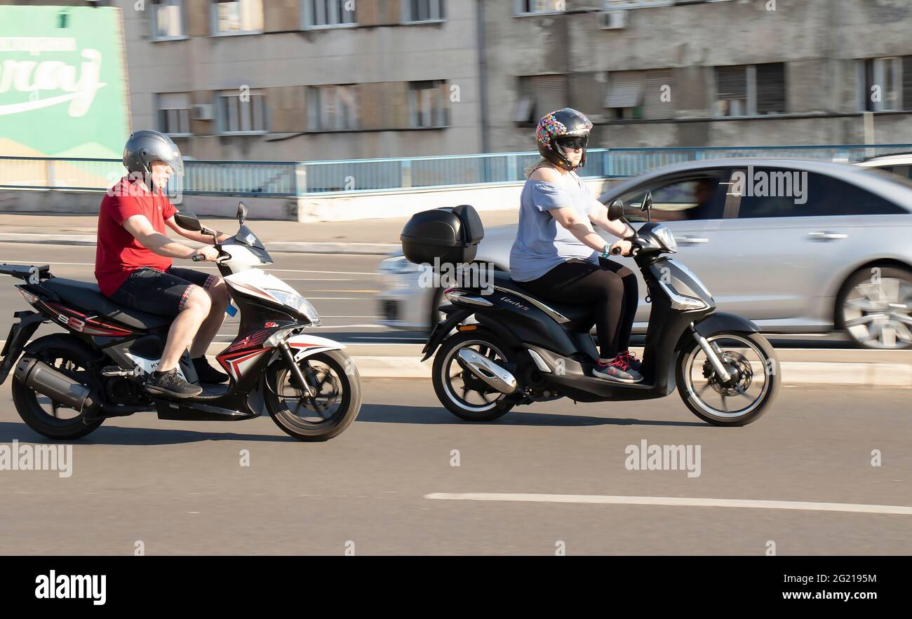 Belgrade, Serbia - June 5, 2021:  People riding  scooter motorbikes  , on city street on a sunny day Stock Photo