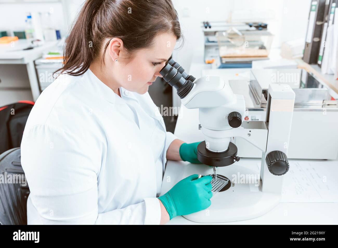 Woman researcher using microscope in lab Stock Photo