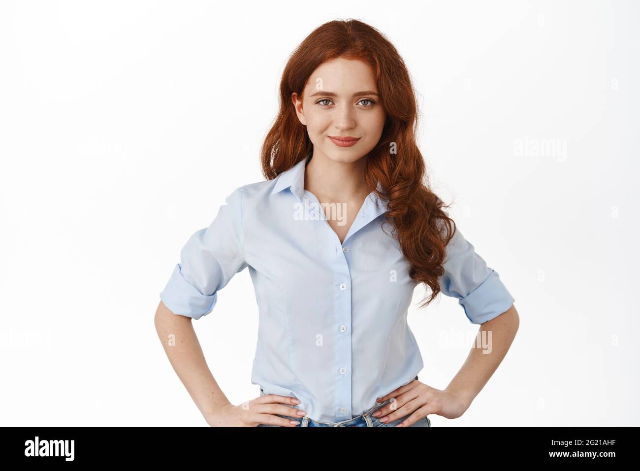 Confident and sassy redhead girl smiling, holding hands on waist ...