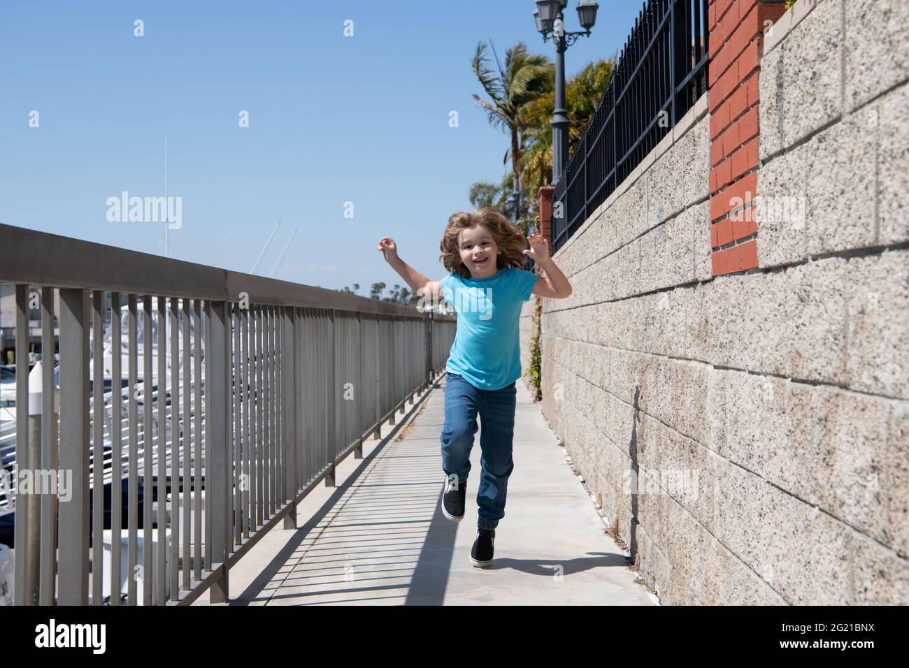 Happy energetic boy child enjoy free time running on promenade during summer vacation, freedom Stock Photo