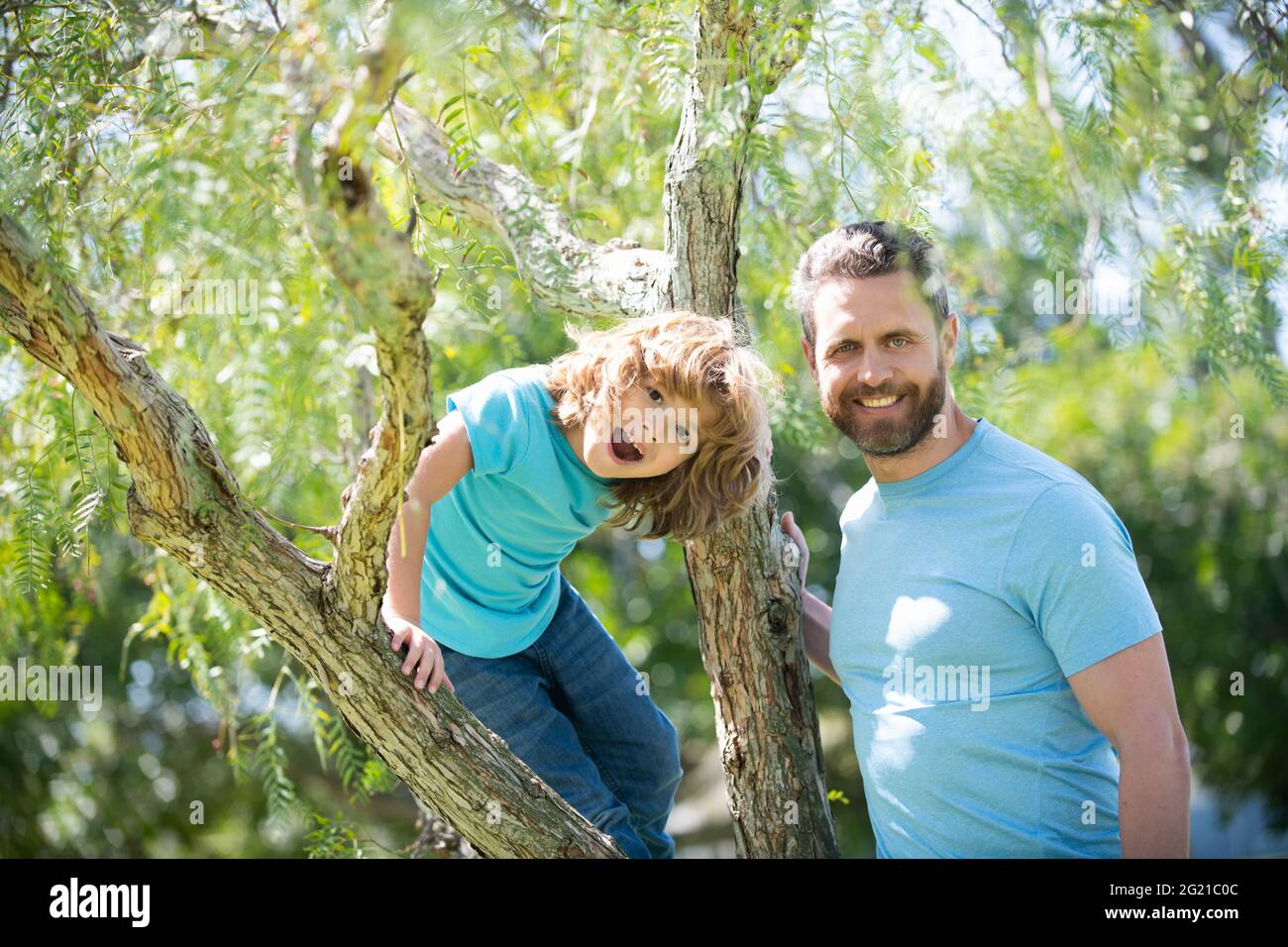 Happy family. Father and son smile sitting on tree. Family fun. Childhood and parenthood Stock Photo
