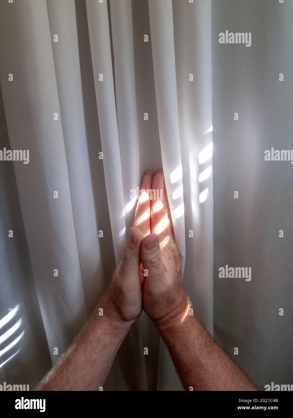 Praying hands, male, curtain and light reflections Stock Photo