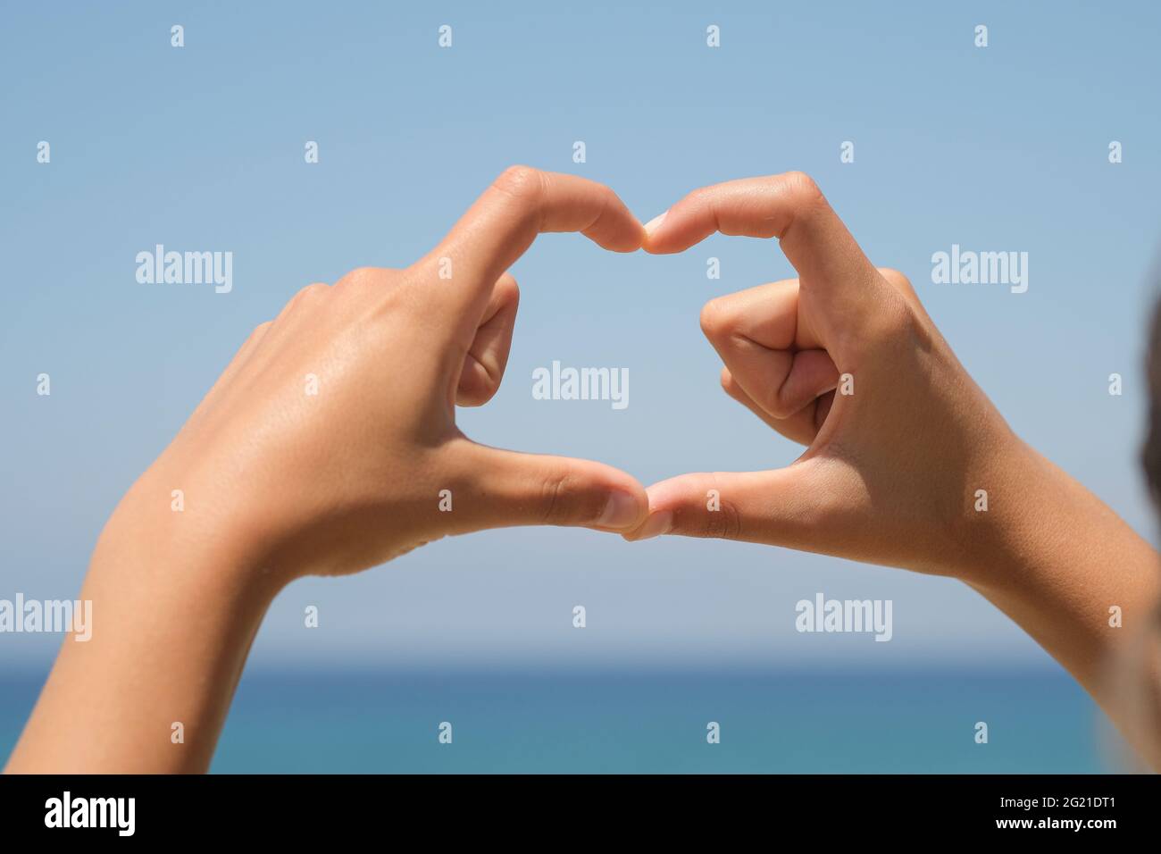 Woman hands while doing herth sign over natural sea horizon background,love  Stock Photo