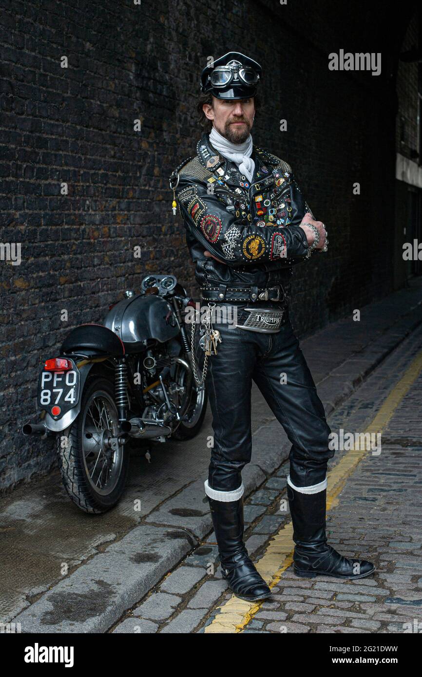 Rocker in cafe racer gear wearing black leather jacket covered in studs,  patches and badges classic british motorcycle in London , UK Stock Photo -  Alamy