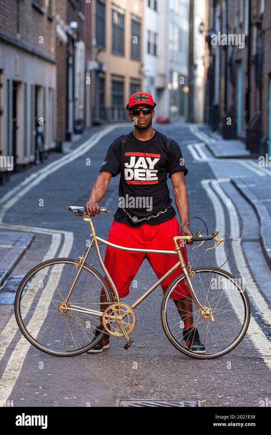 Full length portrait of a stylish black young man with a golden bicycle  in London ,UK Stock Photo