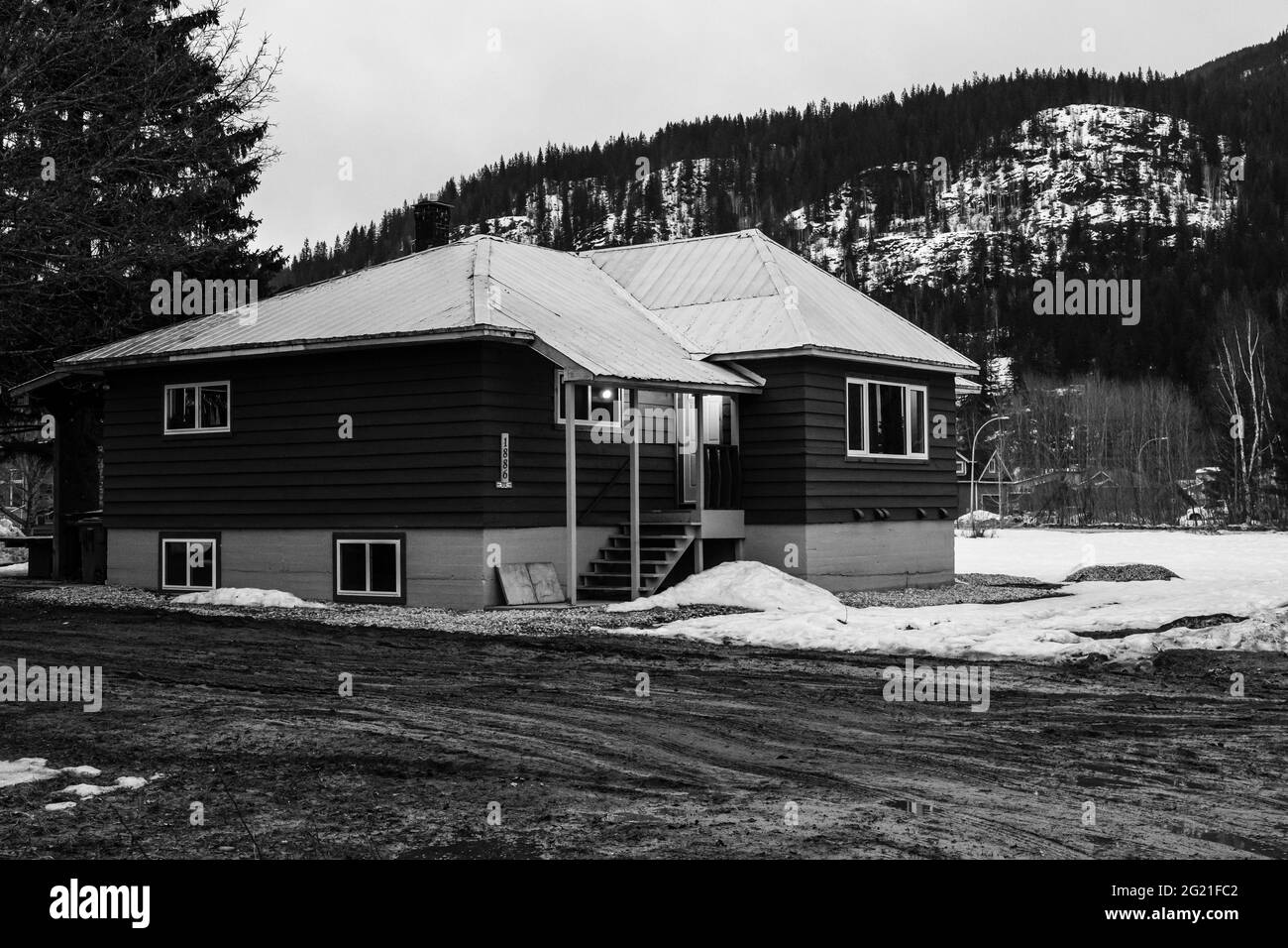 REVELSTOKE, CANADA - MARCH 14, 2021: black and white private home in small town evening time early spring with snow Stock Photo