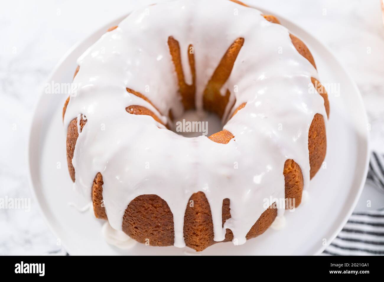 Lemon bundt cake glazed with white glaze on a cake stand Stock Photo