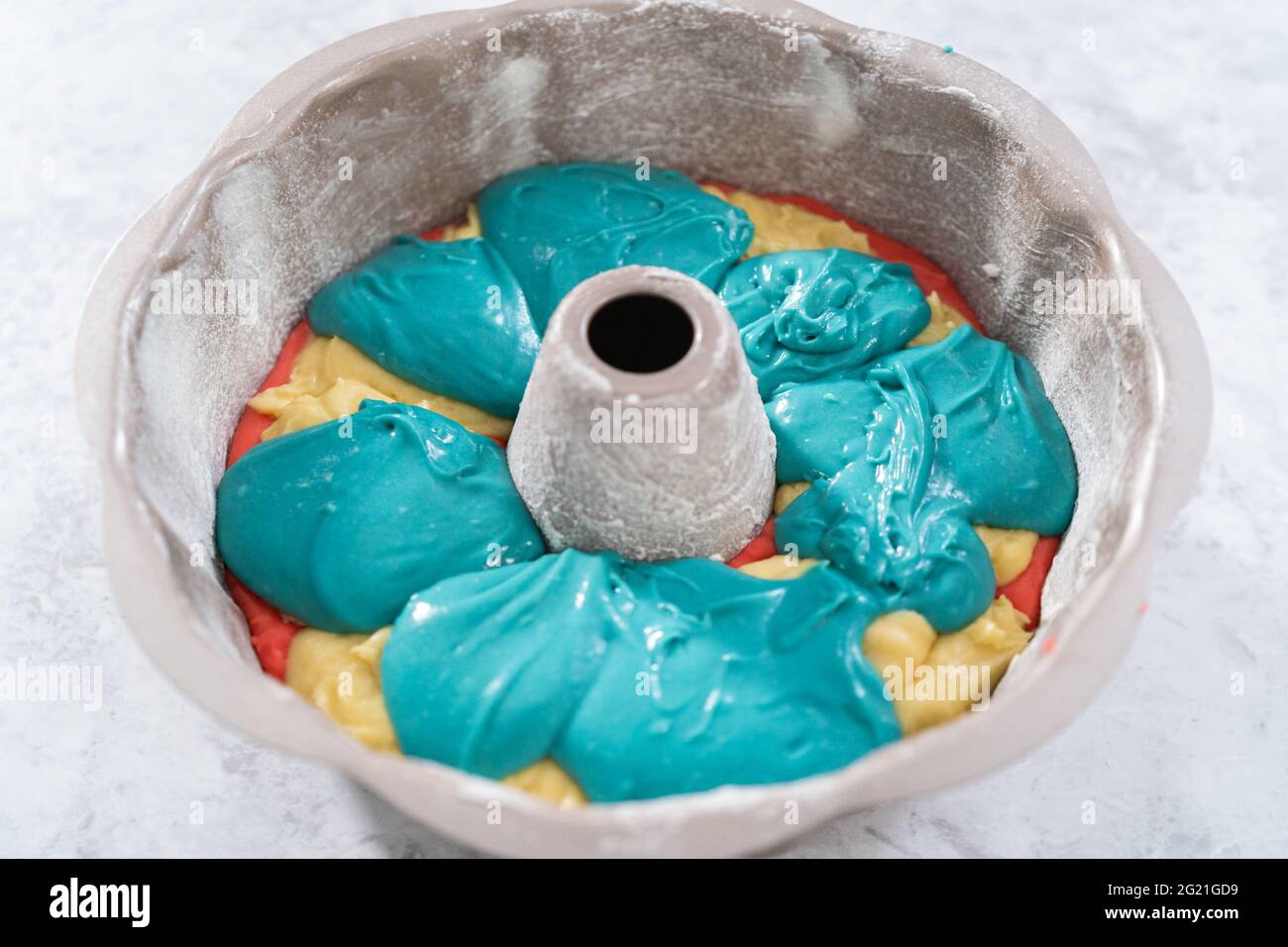Filling bundt cake pan with red, white, and blue cake dought to bake