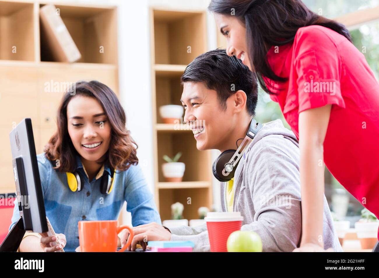 Successful professional team of web designers smiling while testing responsive layout on both mobile phone and desktop PC Stock Photo