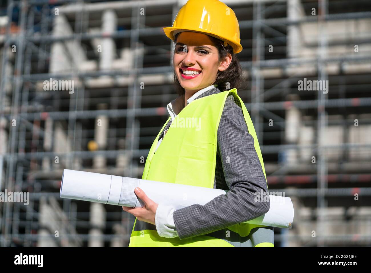 Female civil engineer with construction plans at building site of high-riser Stock Photo