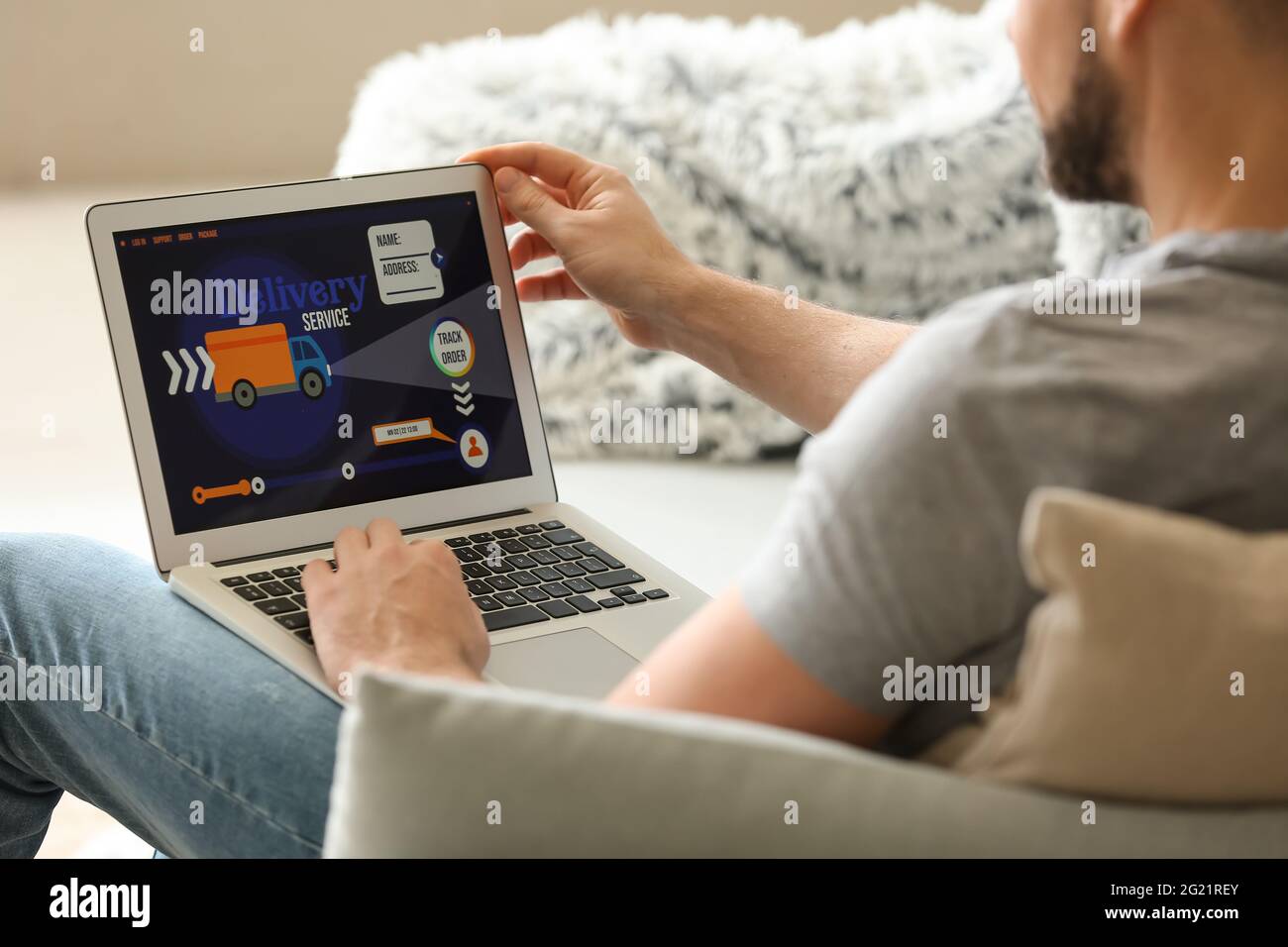 Young man using laptop with open page of delivery service application ...