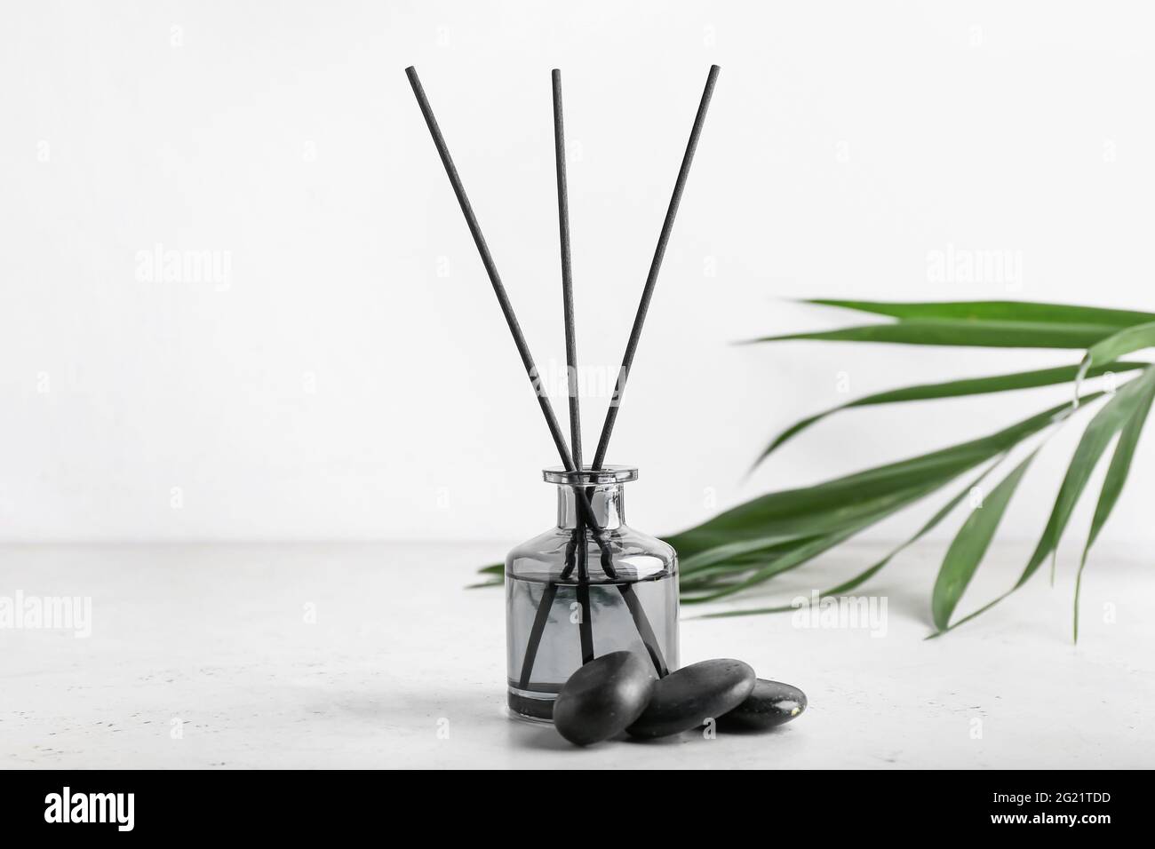 Reed diffuser with tropical leaf and spa stones on white background ...
