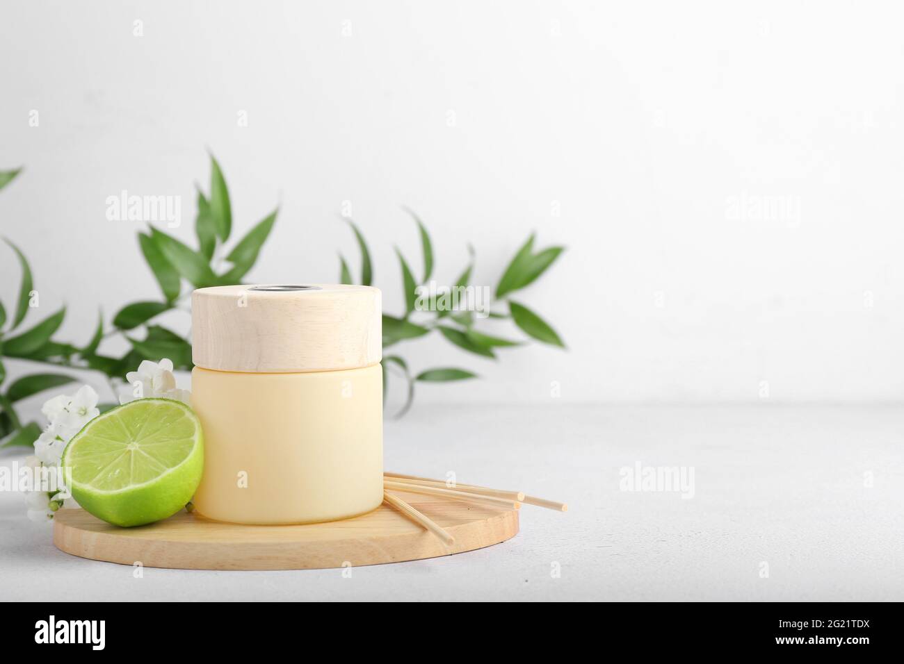 Reed diffuser with lime and flowers on light background Stock Photo
