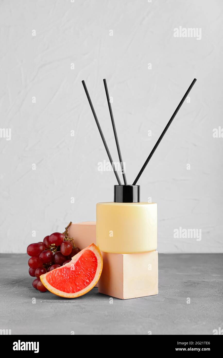 Reed diffuser with fruits on table against light background Stock Photo