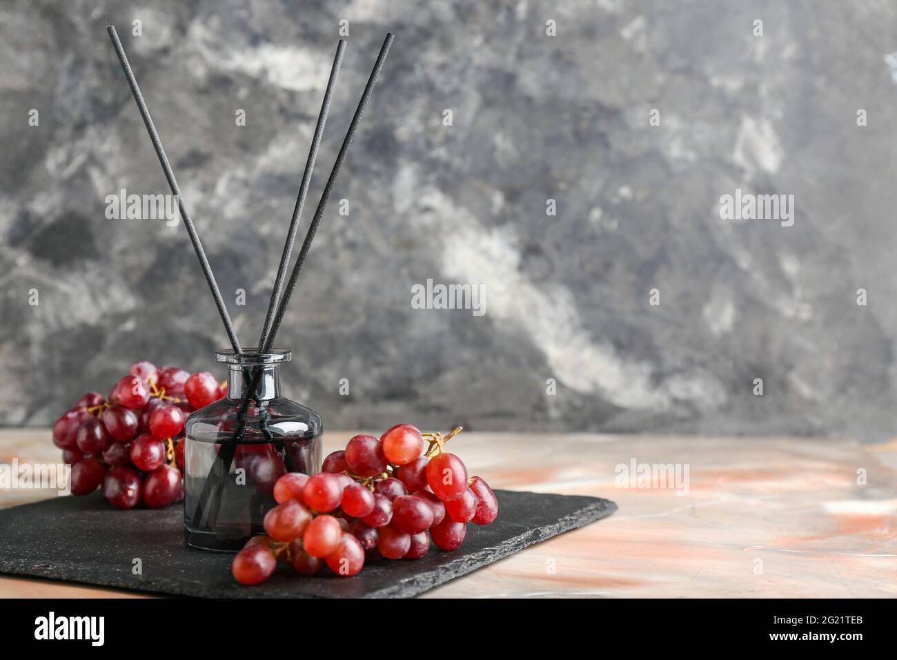 Reed diffuser with grapes on grunge background Stock Photo
