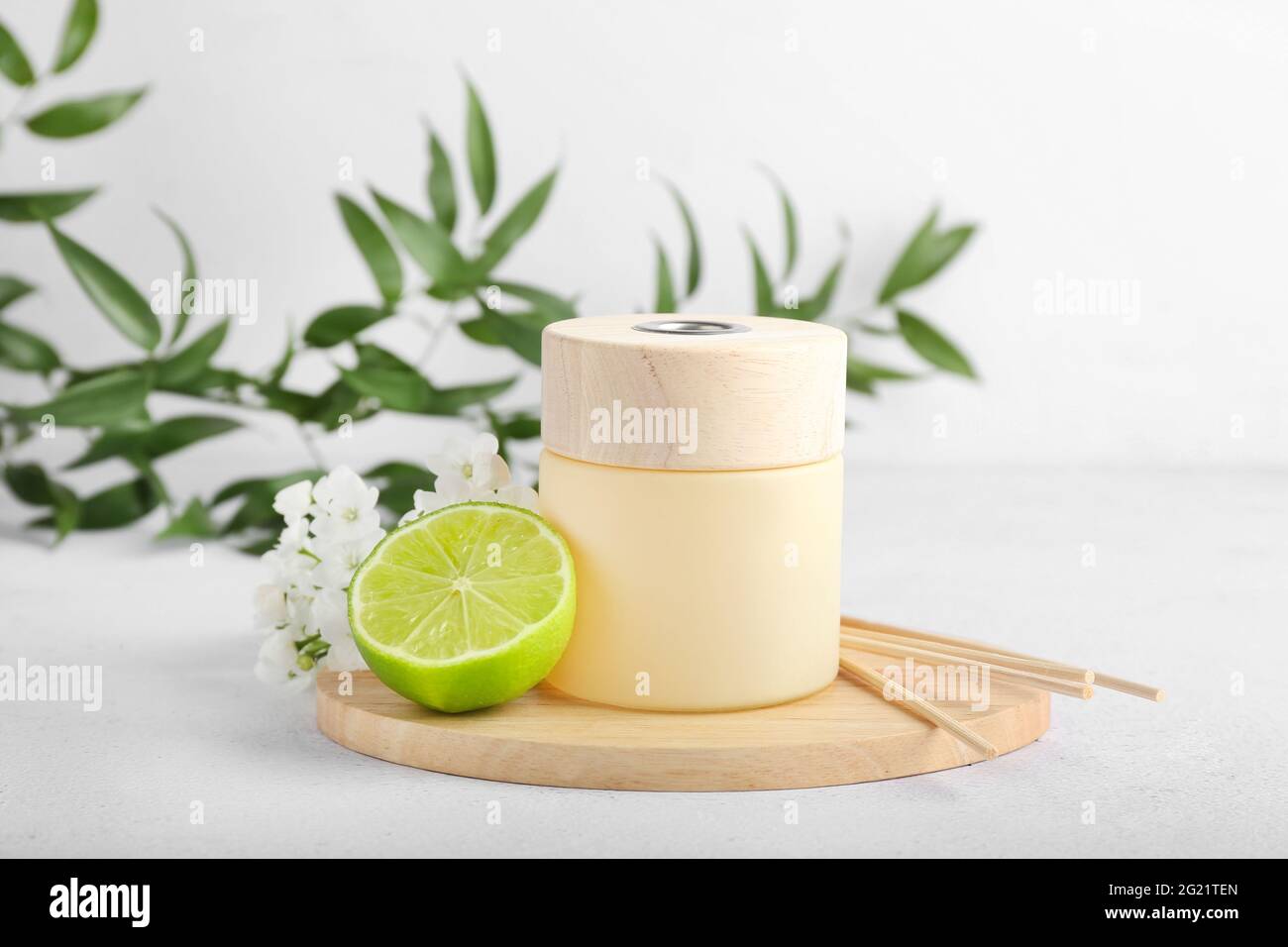 Reed diffuser with lime and flowers on light background Stock Photo