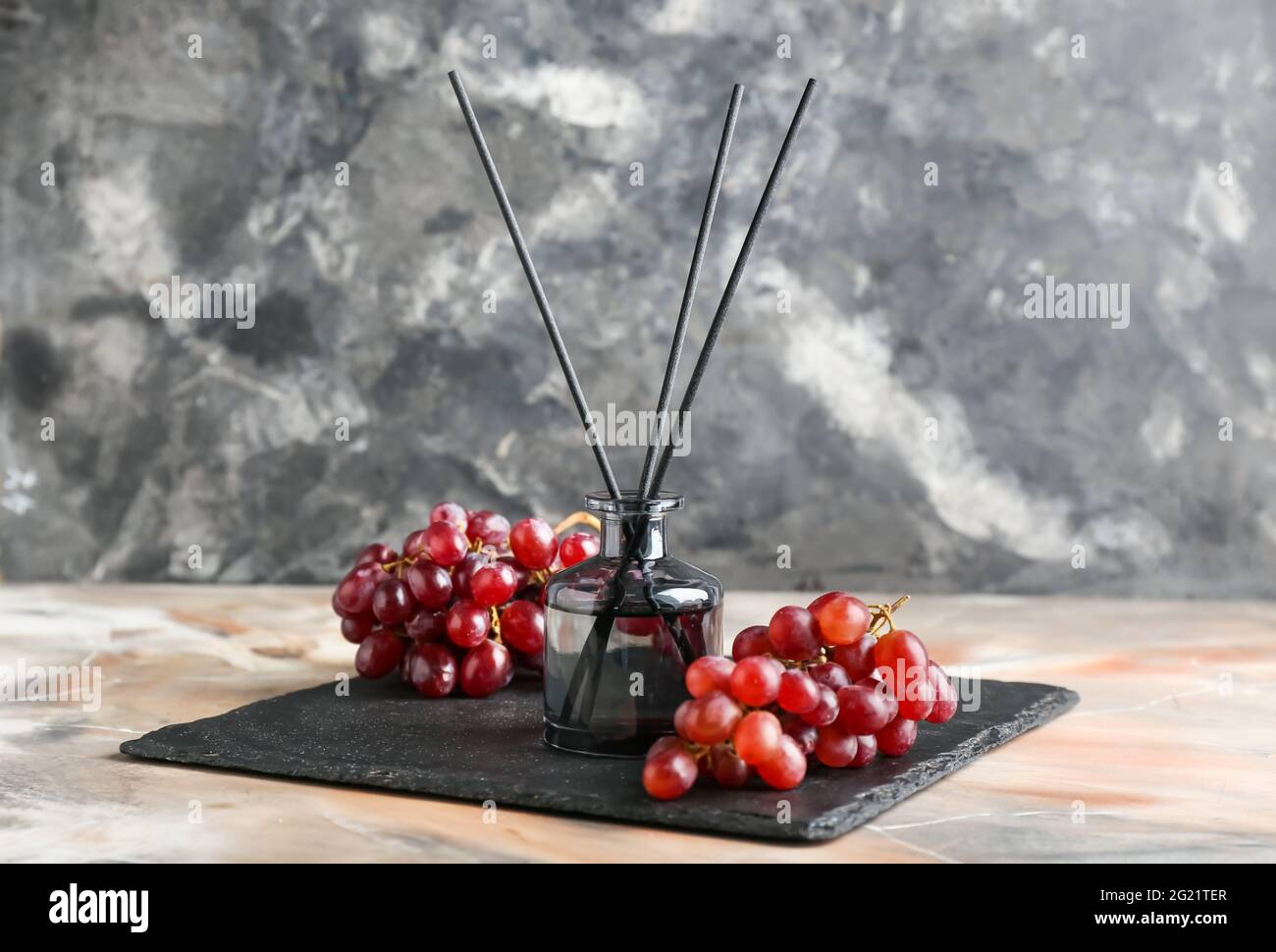 Reed diffuser with grapes on grunge background Stock Photo