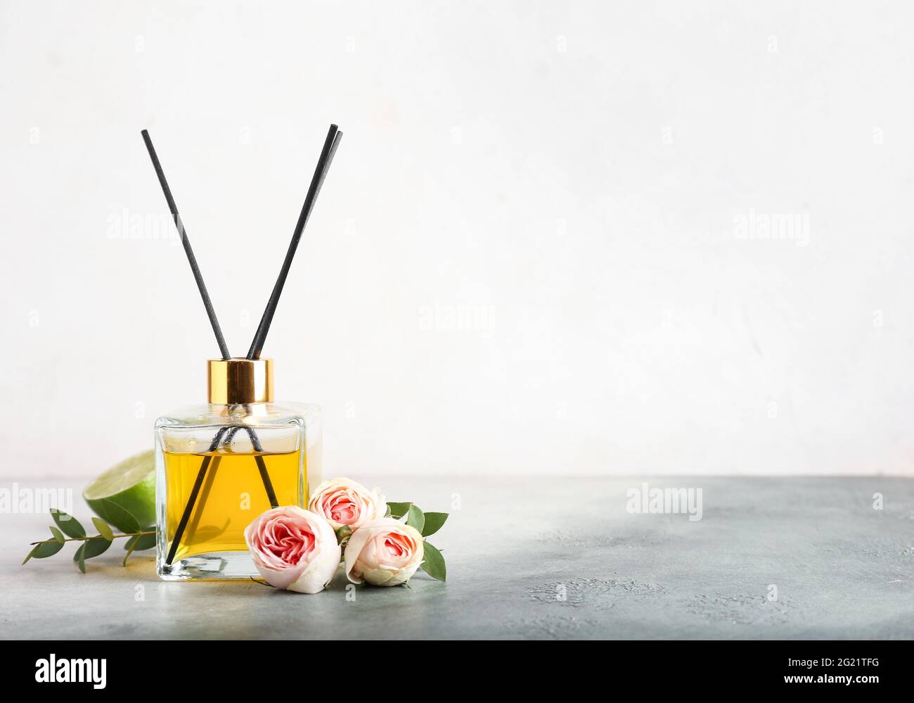Reed diffuser with roses and lime on light background Stock Photo