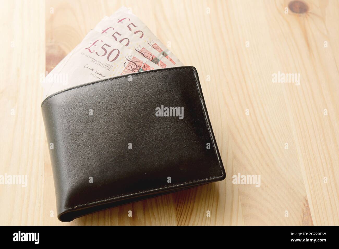 High Angle View Of Modern Black leather Men's Wallet With Pound Cash On The Old Rough Wood Textured Background With Copy Space Stock Photo