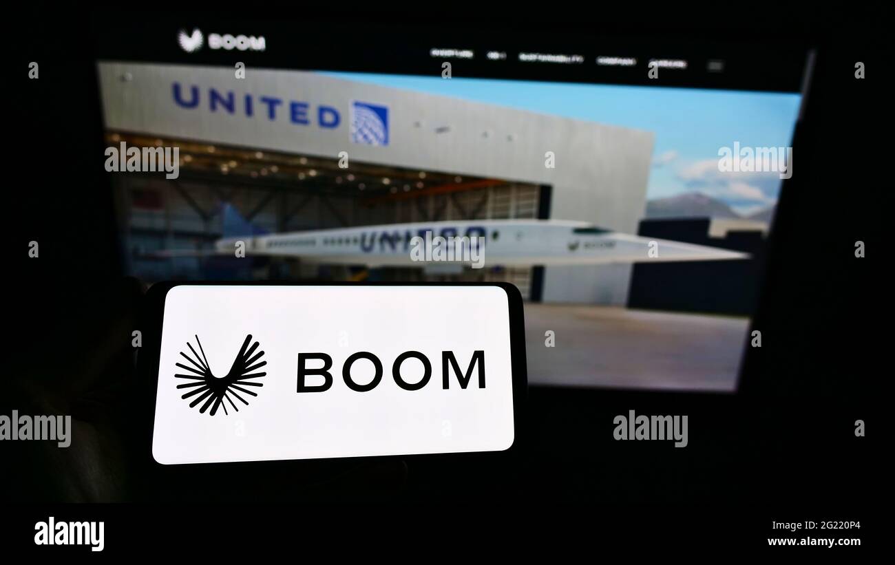 Person holding smartphone with logo of US aerospace company Boom Technology Inc. (Supersonic) on screen in front of website. Focus on phone display. Stock Photo