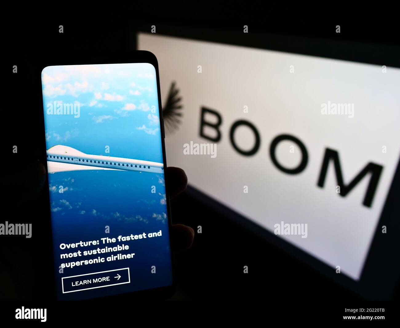 Person holding cellphone with webpage of US aviation company Boom Technology Inc. (Supersonic) on screen with logo. Focus on center of phone display. Stock Photo