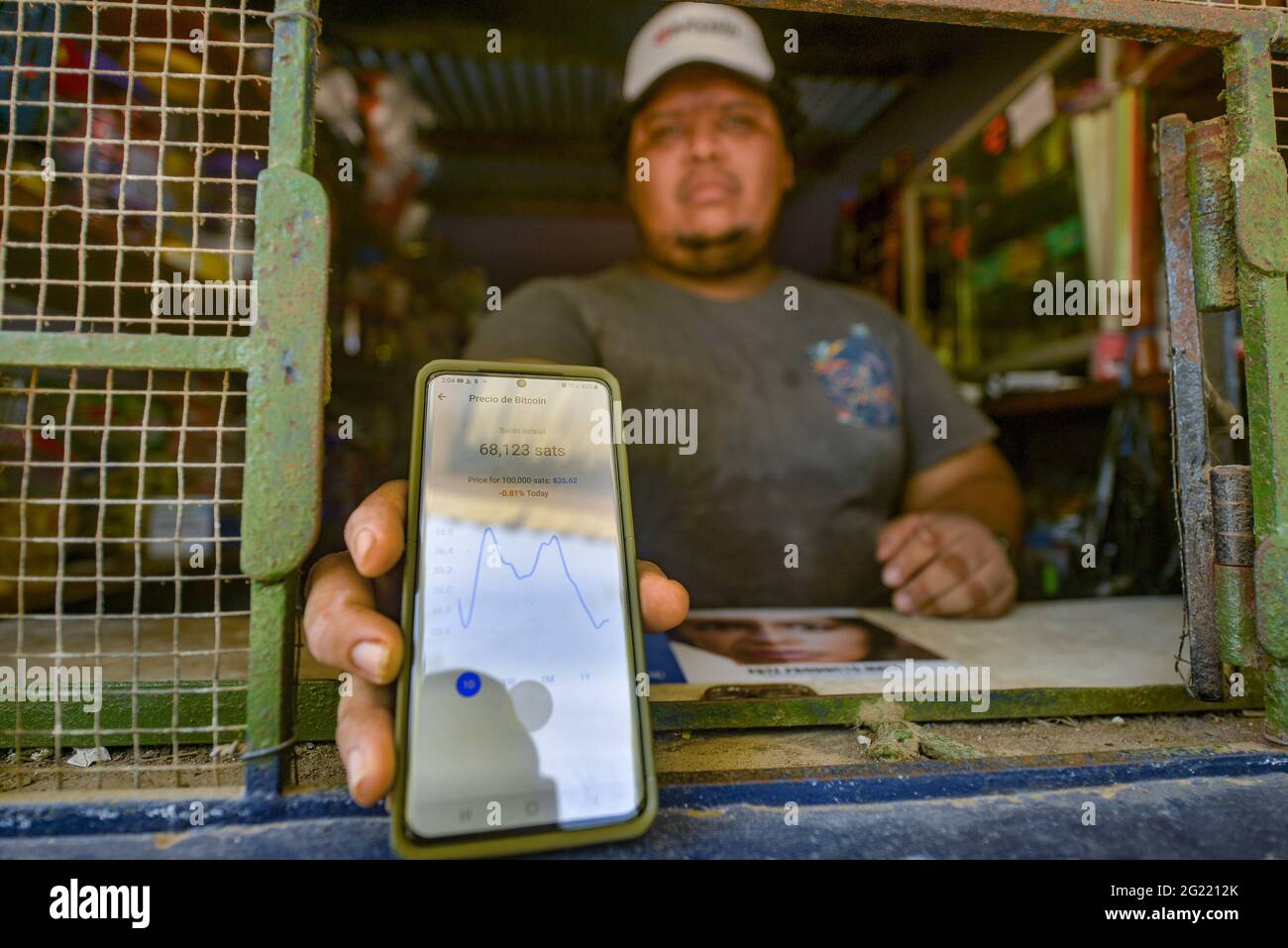 Chiltuipan, El Salvador. 07th June, 2021. A man holds a mobile phone  displaying an application that shows the price ang graph of Bitcoin.  Salvadoran President Nayib Bukele has announced that he will