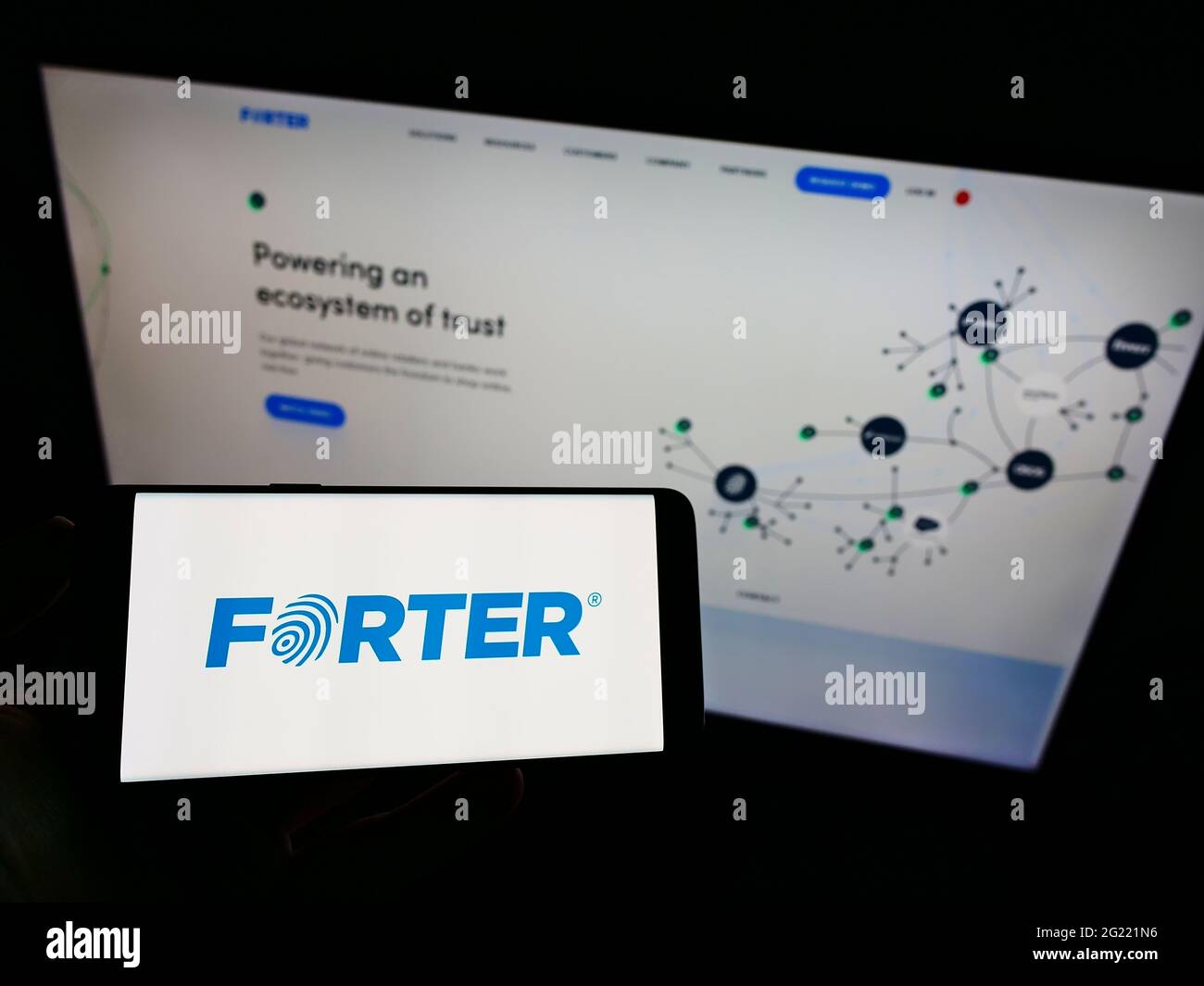 Person holding smartphone with logo of fraud prevention software company Forter Inc. on screen in front of website. Focus on phone display. Stock Photo