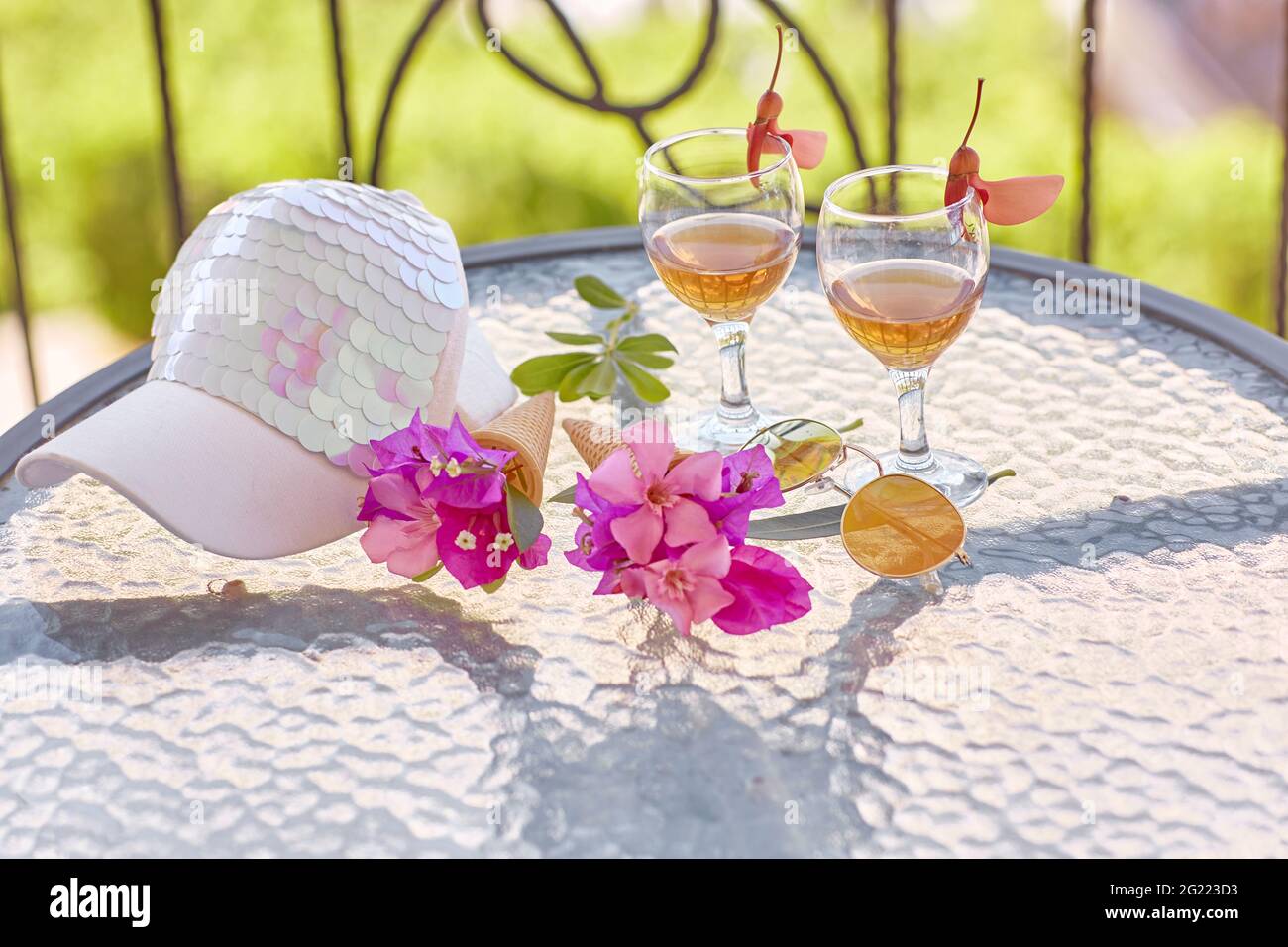 Summer cocktails background on bright green background with pink flowers of bougainvillea. Bright women cap. Summer starts creative concept. High quality photo Stock Photo