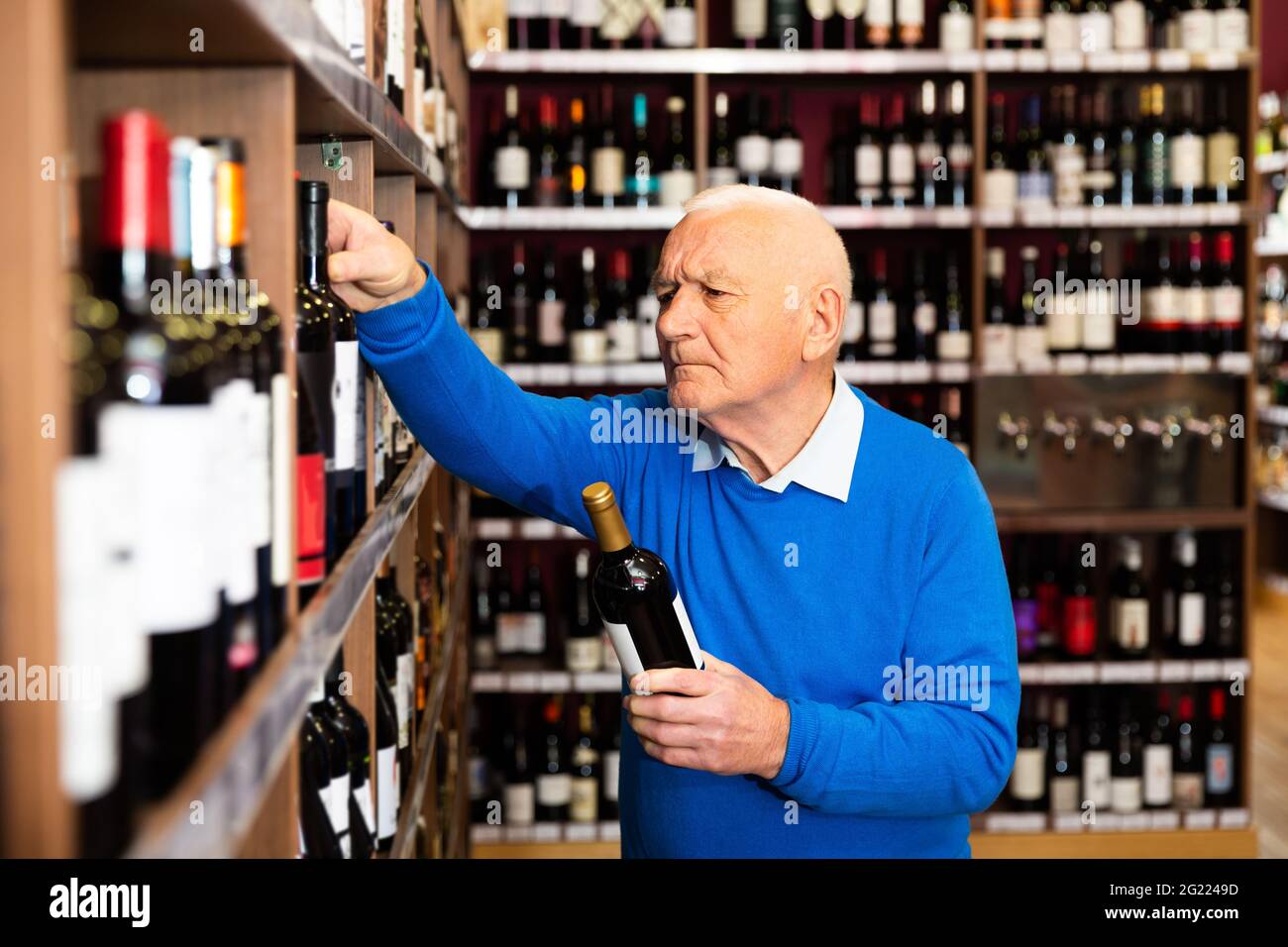 Mature man chooses red wine Stock Photo