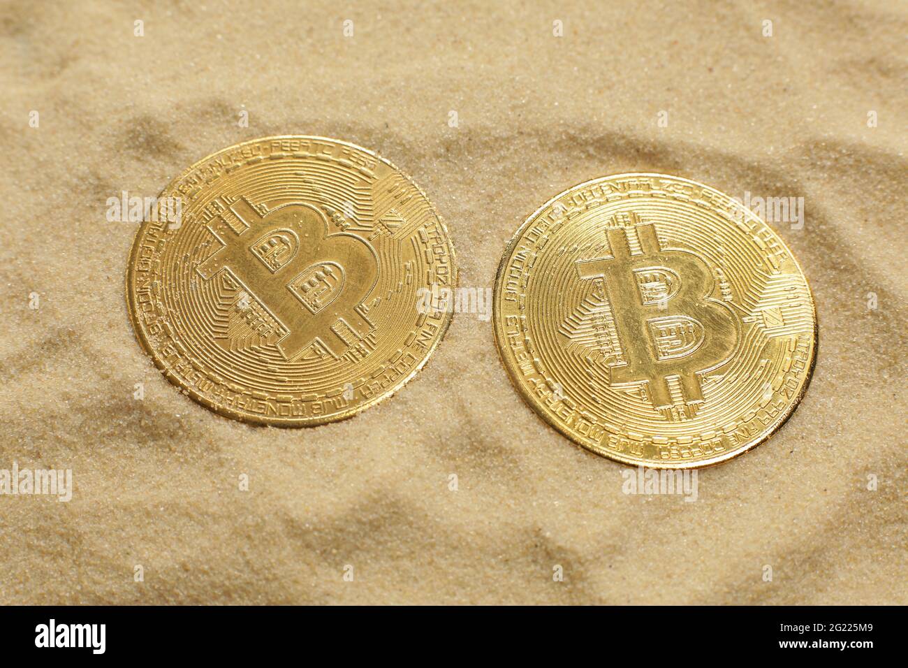 Two bitcoin coins on the sand. Close-up Stock Photo - Alamy