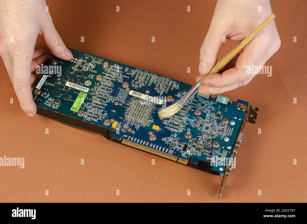 Graphics card brand Gigabyte NVidia GeForce on brown background. Man sweeps  dust off the Dusty computer components with brush. Repair, maintenance of  Stock Photo - Alamy