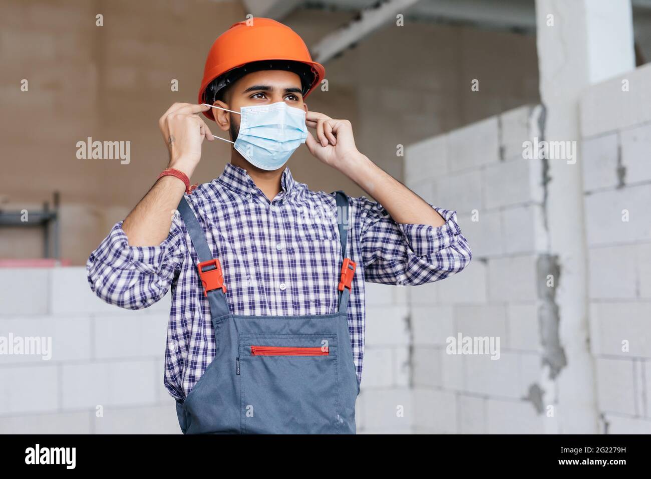 Construction worker portrait on white wall posing with face mask covid -19 prevention Stock Photo