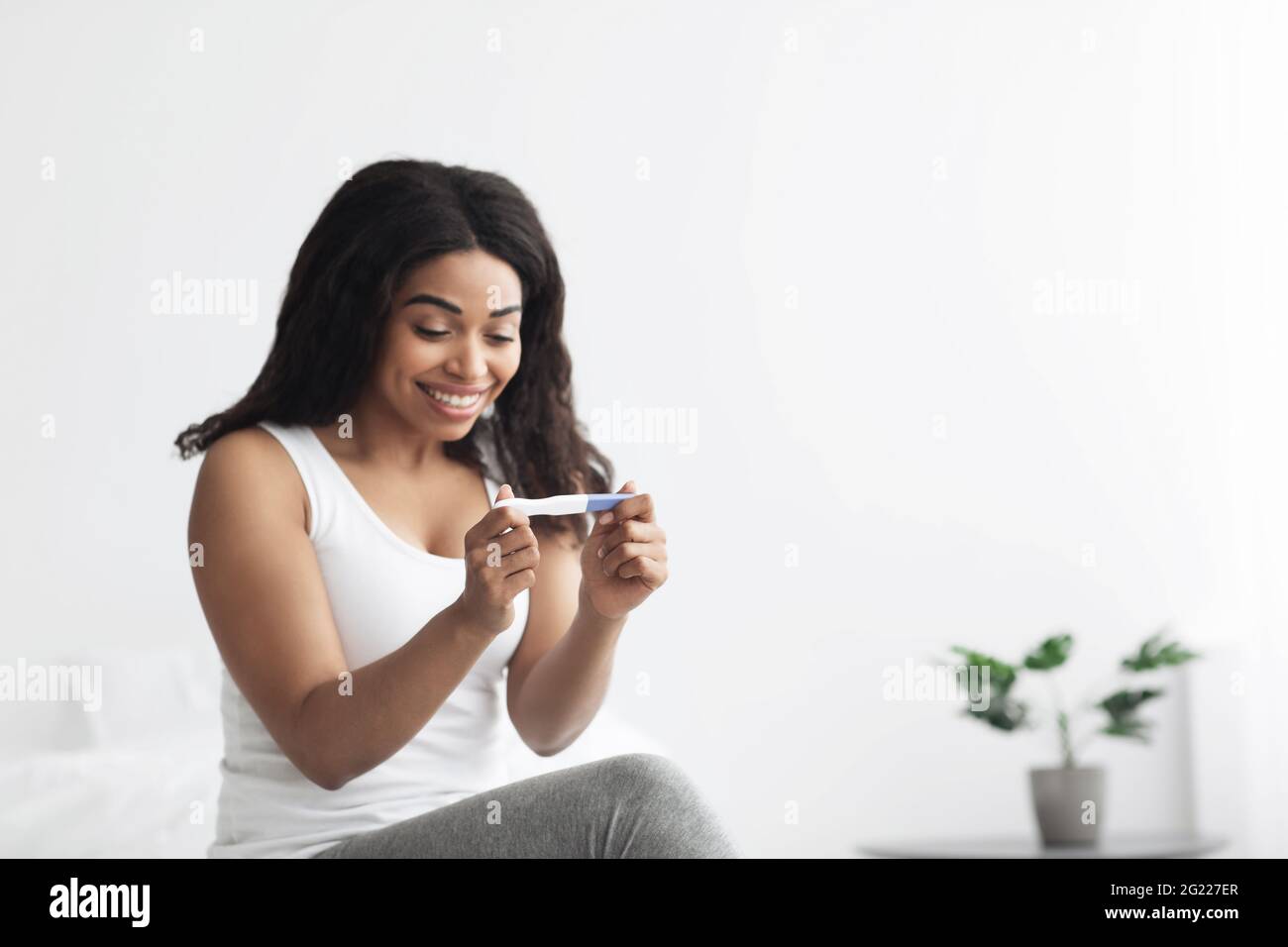 Happiness and expectation of child. Happy african american lady looking at positive pregnancy test Stock Photo