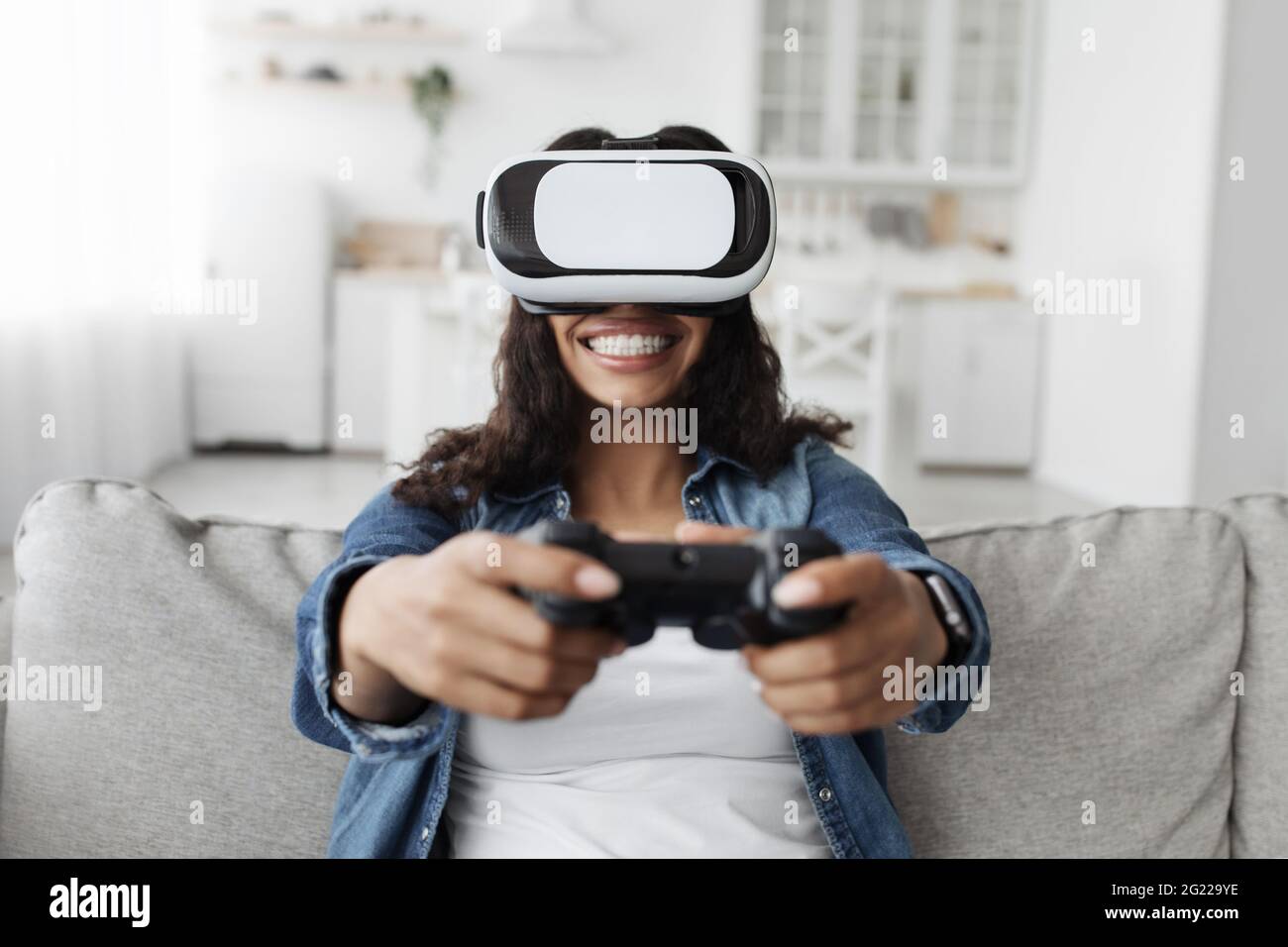 Happy african american woman in vr glasses with joystick, passionately  playing in online games sitting on sofa Stock Photo - Alamy