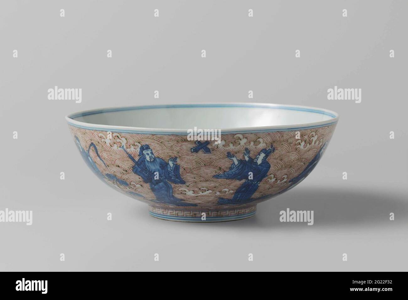 Bowl with the Eight Immortals and Shoulao. Bowl of porcelain with flared wall, painted in underglaze blue and red. On the outside the eight immortals standing on marine animals, against a background of foamy waves; On the bottom shoulao with a deer with a mushroom in his mouth against a background of foamy waves and clouds; Around the foot ring a decorative border with Meander motif. On the underside the six character mark Chenghua in a double circle and an old label with 'Marked Ching-Hua period 1465-1488 1888 A. Stapnell'. Middle blue with copper red. Stock Photo