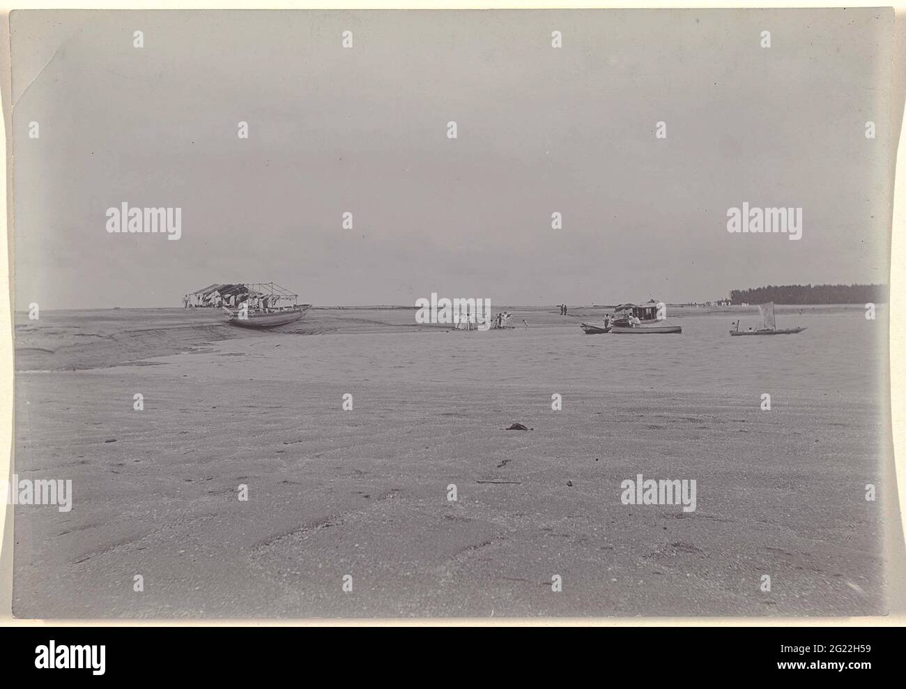 Picnic on the beach. Drumed river bed or beach with boats and company. Picnic on the beach at the Surinamer River. Different boats and a shack. Part of a group of objects from the Wesenhagen family in Suriname. Stock Photo