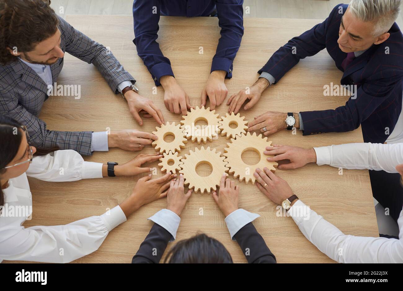 Team of business people connect some gearwheels as metaphor for effective teamwork Stock Photo
