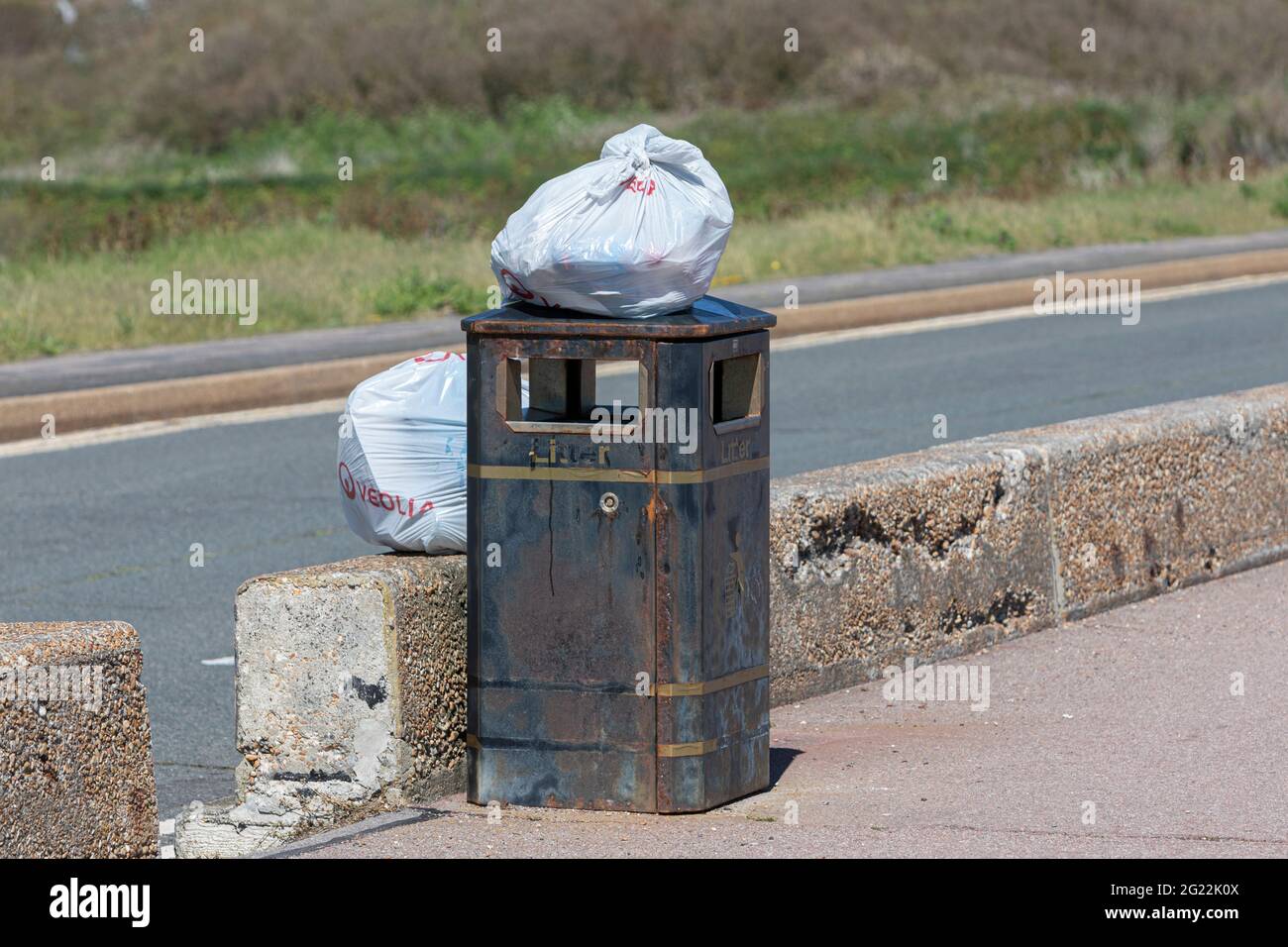 Bags of refuse waiting for collection on a rusty waste bin on Prince’s
