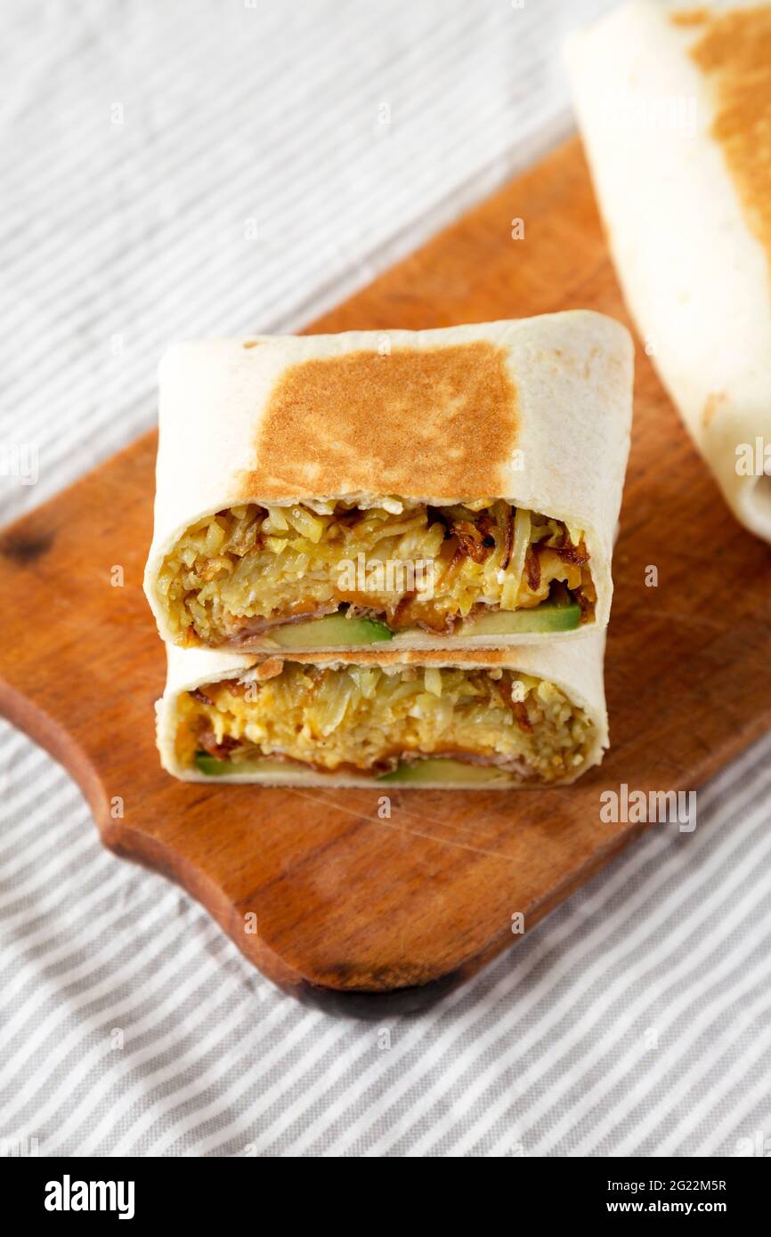 Homemade Breakfast Egg Burrito with Avocado and Bacon on a rustic wooden board, side view Stock