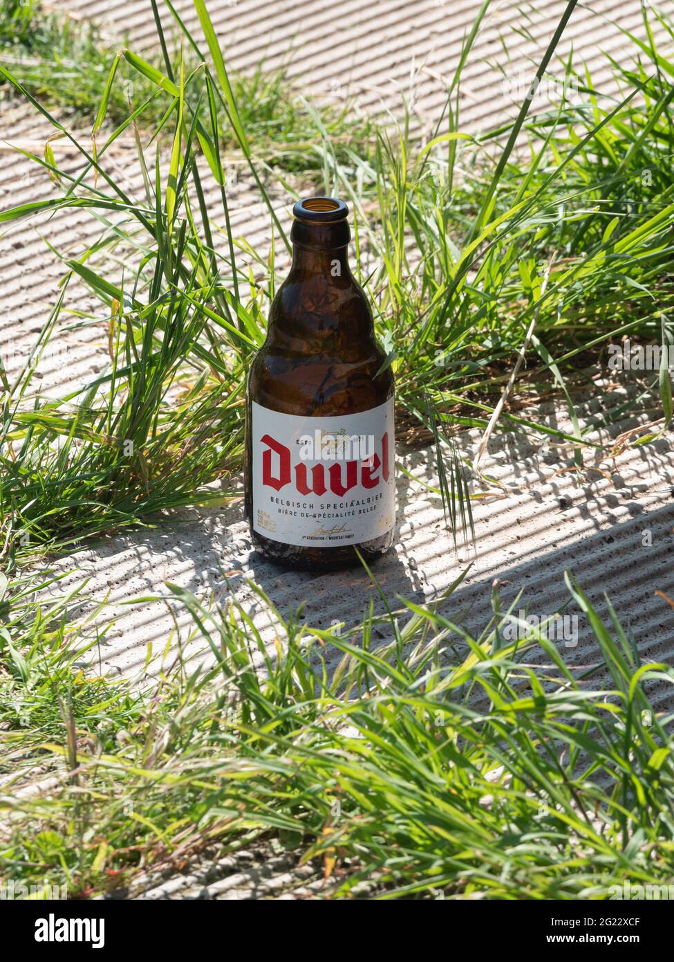 Basel, Belgium, May 30, 2021, Empty bottle of Belgian beer called Duvel left on the side of a road Stock Photo
