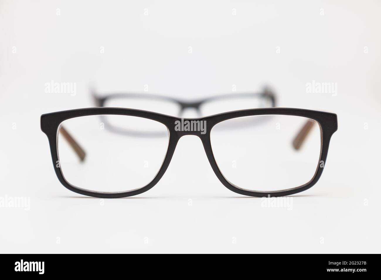 Two pairs of eyeglasses placed on a white surface. The closest ones are ...